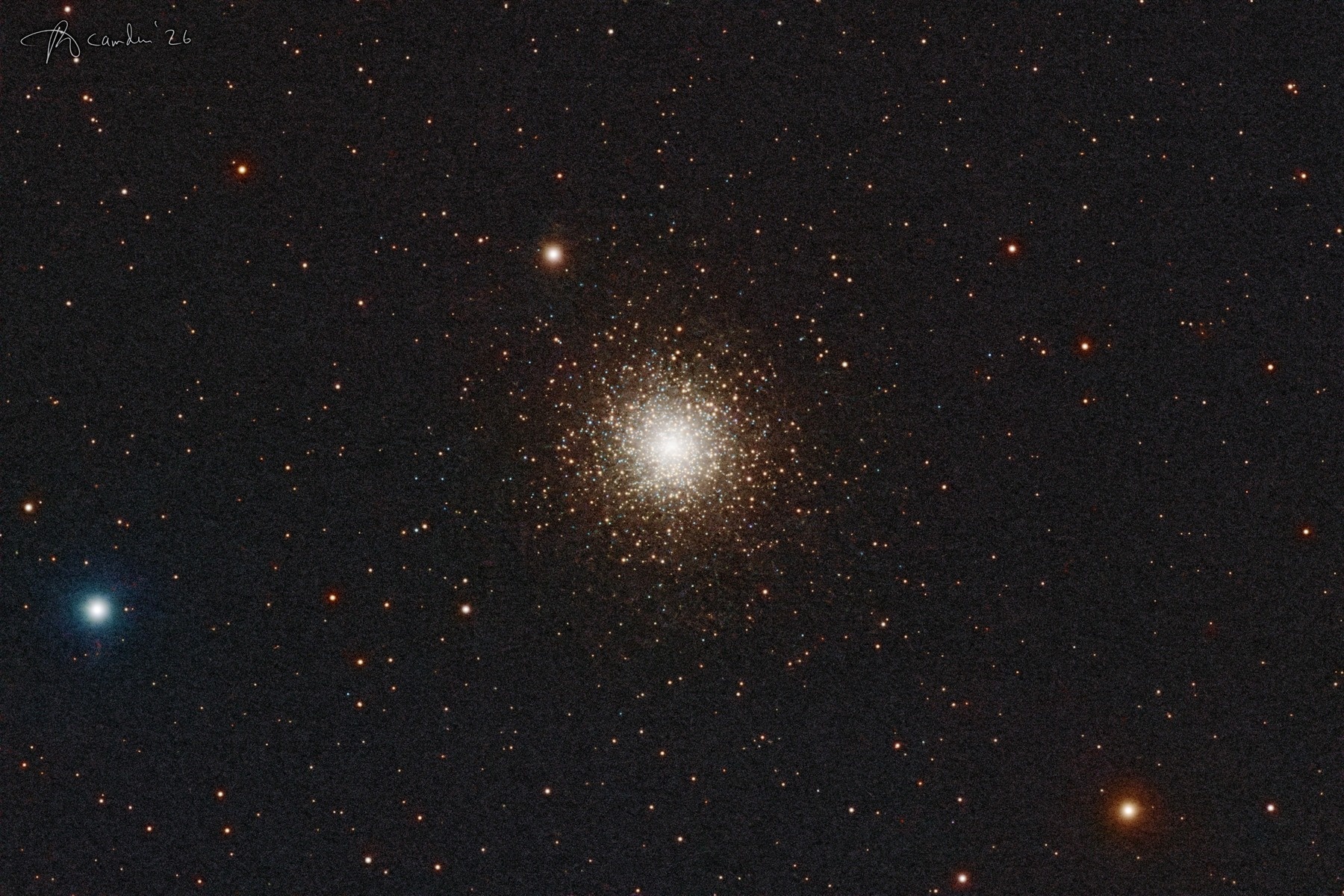 M15, the Great Pegasus Cluster — a dense ball of thousands of stars, white at the centre and gold and blue toward the edges, in a field of orange and white stars